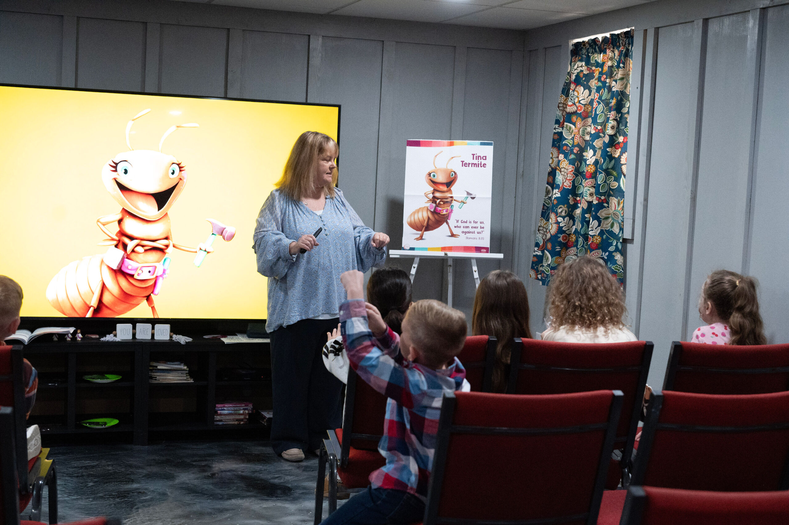 Children listening to a Bible lesson with a cartoon character on the classroom screen