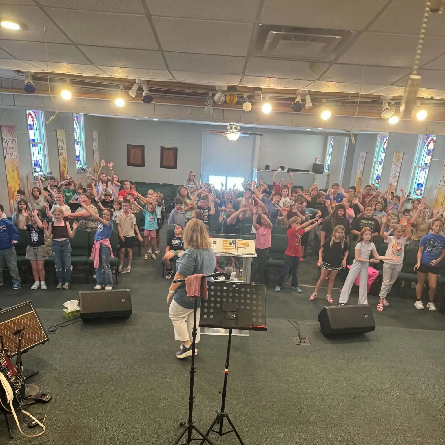 Children and leaders raising their hands during a group activity in the sanctuary