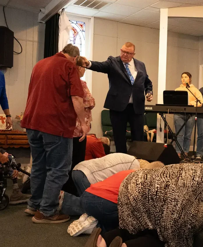 Pastor praying with people at the front of the Maple Street sanctuary