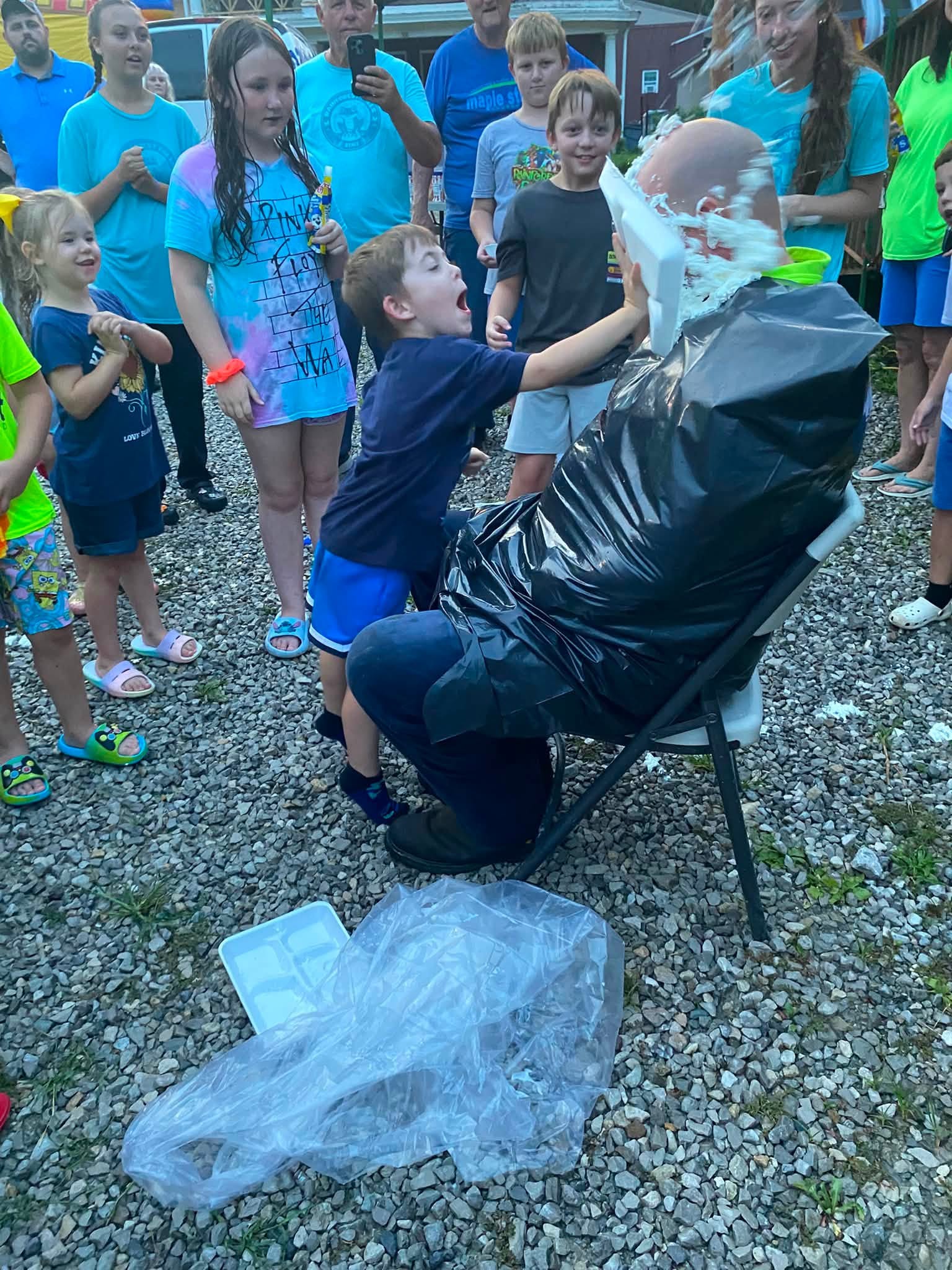 Children and volunteers laughing during an outdoor VBS pie-in-the-face activity