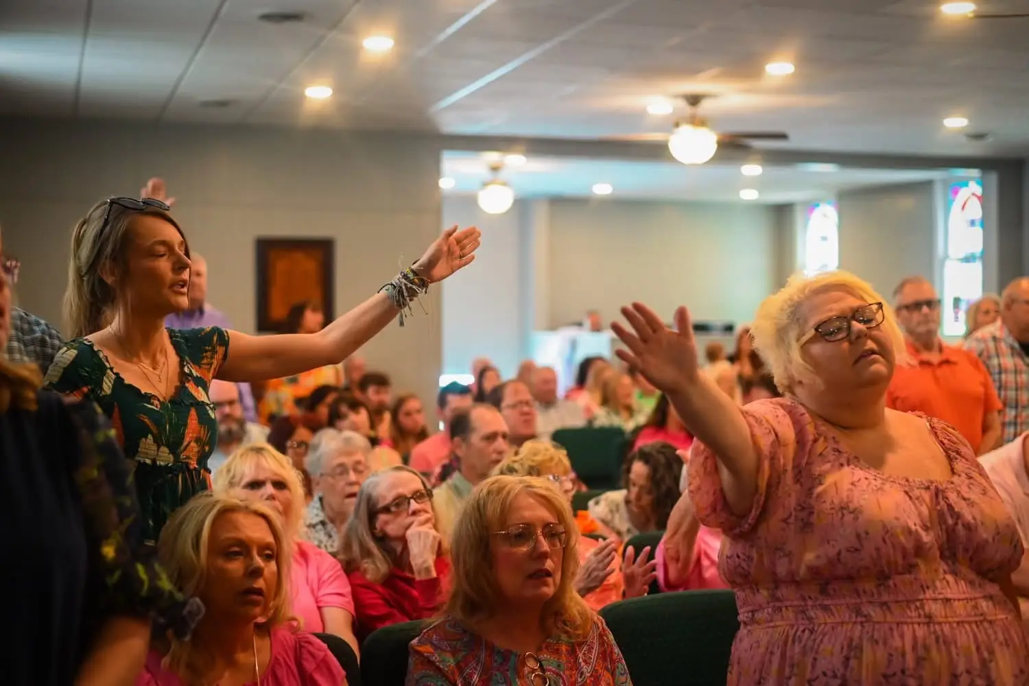 Congregation worshiping with raised hands in the Maple Street sanctuary