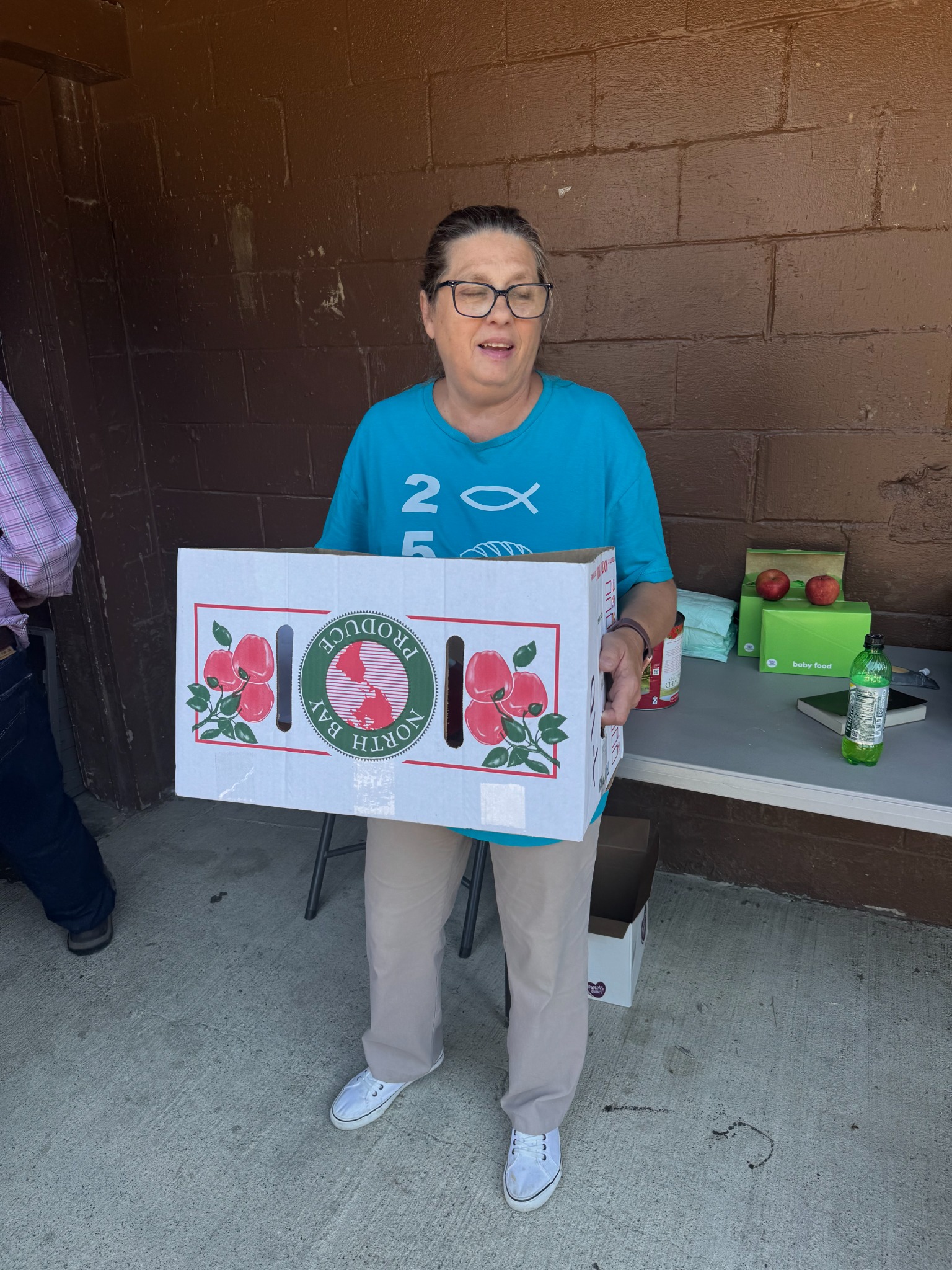 A Maple Street pantry volunteer holds a box of food