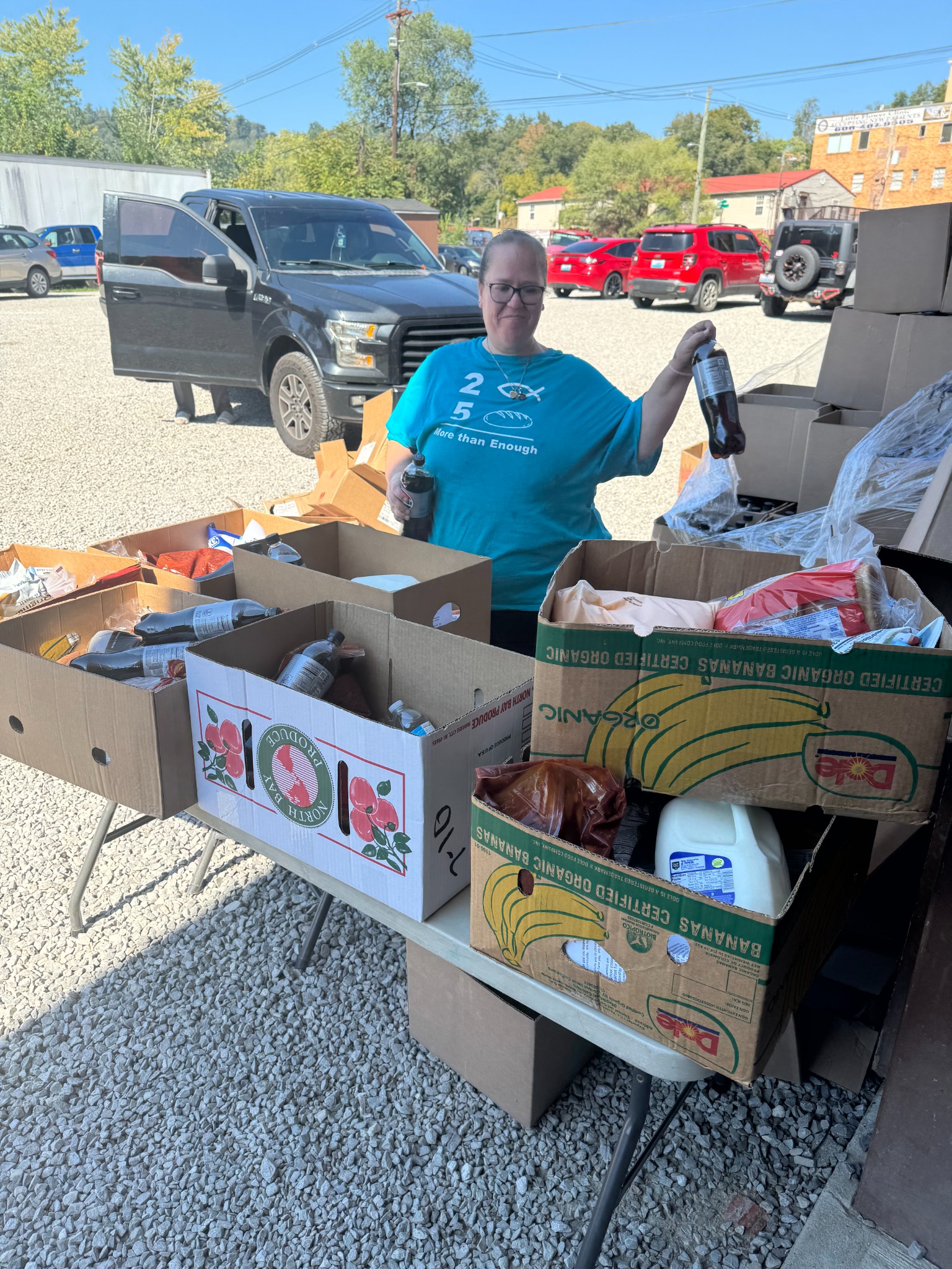 A pantry volunteer stands behind food boxes ready for distribution