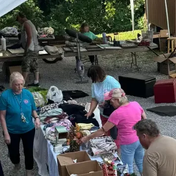 Volunteers arranging donated items on tables at an outdoor community event