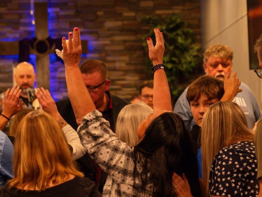 People gathered in prayer with raised hands near the sanctuary platform