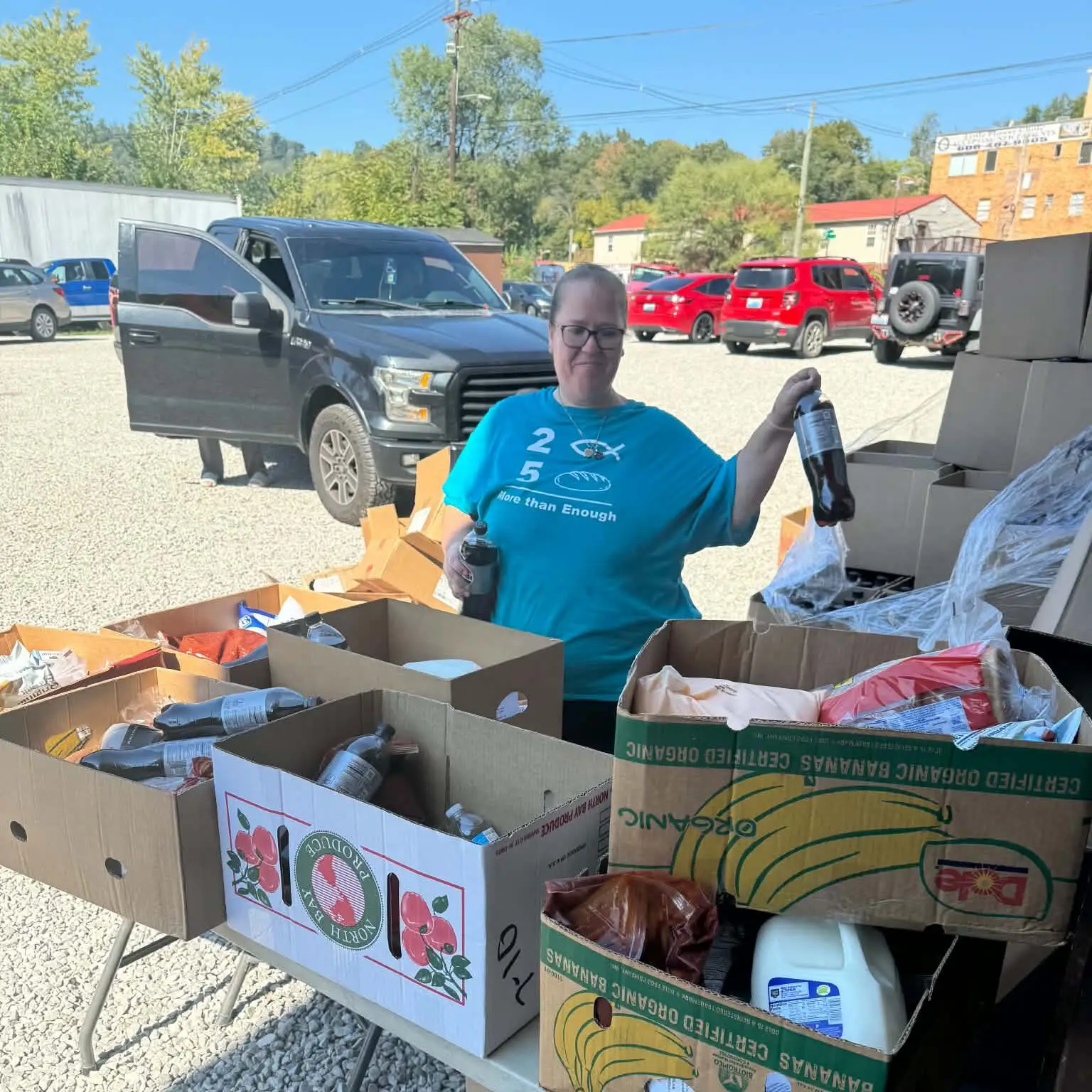Food pantry volunteer standing beside boxes of groceries for distribution