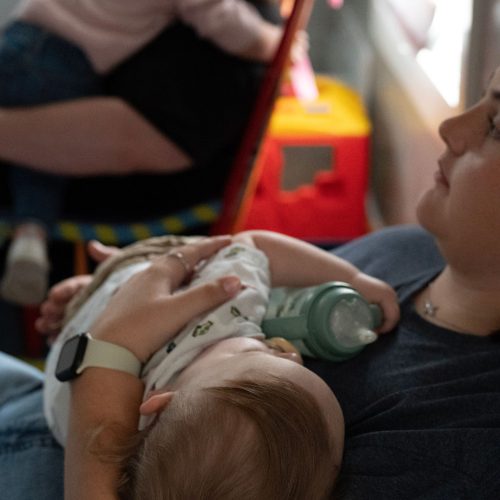Nursery volunteer holding and feeding a baby
