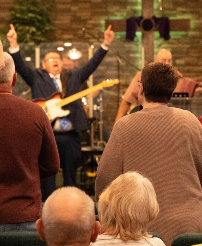 Worship leader raising his hands beside a guitar in the sanctuary