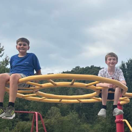 Two boys sitting on playground climbing equipment